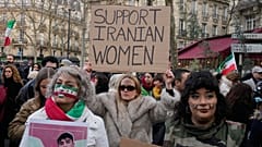 Una manifestante que apoya a la ciudadanía iraní muestra un cartel que reza, en inglés, "apoyad a las mujeres iraníes"