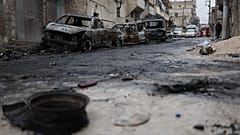 Menschen gehen an ausgebrannten Autos im Viertel Sheikh Maqsoud vorbei. Dort kämpfen Staatstruppen und kurdische Kämpfer in der Stadt Al im Norden.