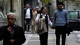 eople walk on a sidewalk in northern Tehran, Iran