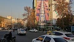  تمر المركبات أمام لافتة تحمل صورة معادية للولايات المتحدة وإسرائيل، في ساحة فلسطين بوسط طهران، إيران، يوم الأحد 4 يناير 2026.