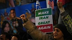 Protesters hold up placards and flags as they demonstrate outside the Iranian Embassy in London, 12 January 2026