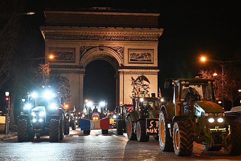 Des agriculteurs conduisent leurs tracteurs sur l'avenue des Champs-Élysées, le mardi 13 janvier 2026 à Paris
