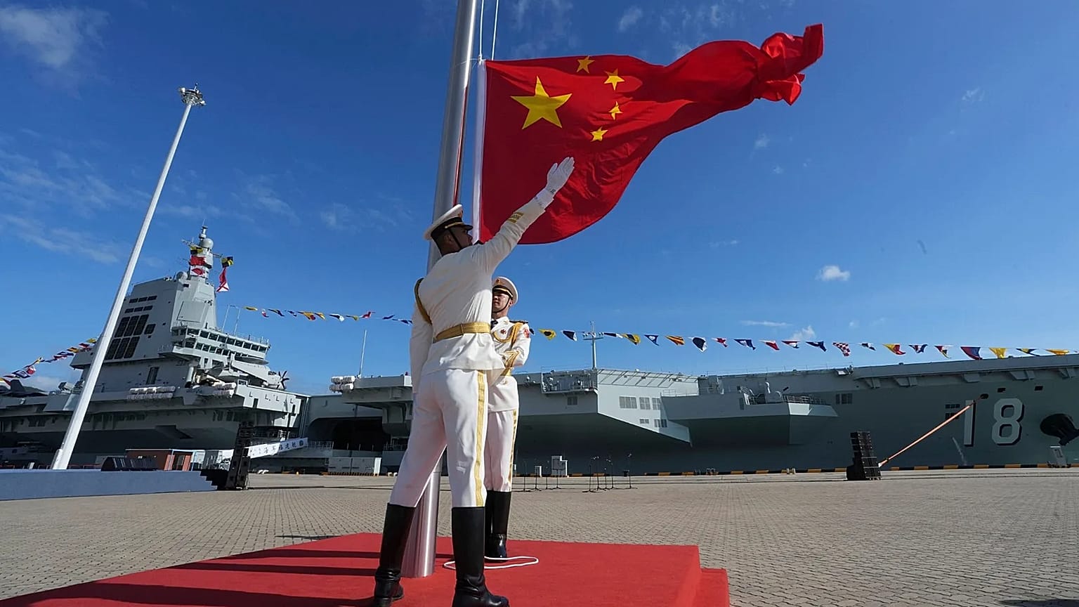 Honour guard members raise the Chinese national flag during the commissioning of China's third aircraft carrier in Hainan Province, 5 November, 2025