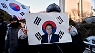 Güney Kore'de eski Devlet Başkanı Yoon Suk Yeol'un bir destekçisi, başkent Seul'de mahkeme önünde pankart tutuyor, 13 Ocak 2026.