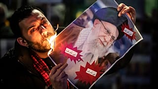 Ein Demonstrant verbrennt während einer Kundgebung in der Schweiz ein Bild von Ayatollah Ali Khamenei mit einer Zigarette.