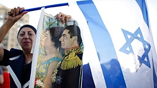 امرأة إسرائيلية من أصل إيراني تحمل علم إسرائيل وصورة للشاه محمد رضا بهلوي للتضامن مع الشعب الإيراني في هولون قرب تل أبيب، 23 يونيو 2009.