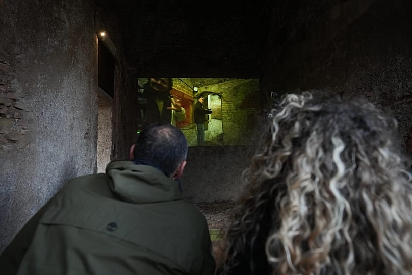 Зрители смотрят прямую трансляцию экскурсии по недавно восстановленному подземному Дому Грифонов.