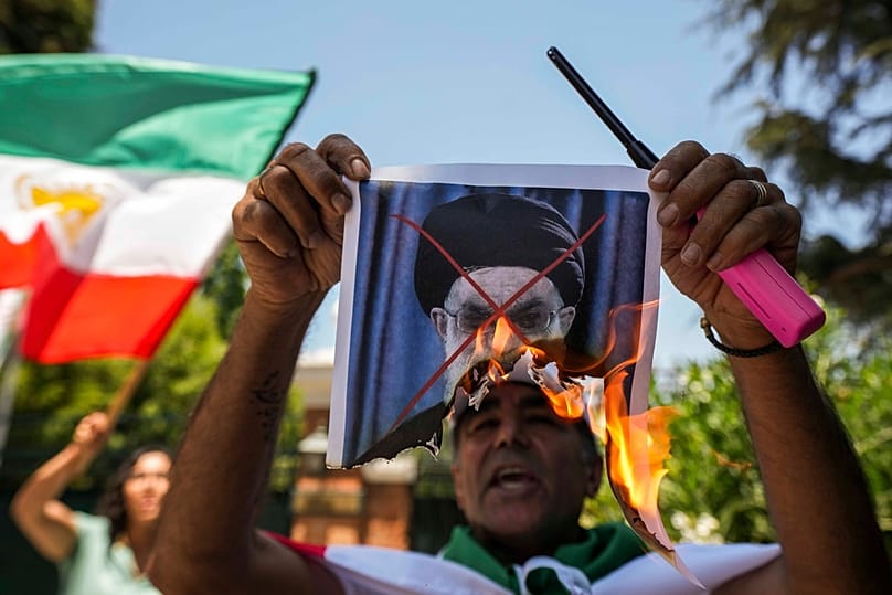 متظاهر يحرق صورة المرشد الأعلى الإيراني علي خامنئي خلال تجمع دعم للاحتجاجات المناهضة للنظام أمام السفارة الإيرانية في سانتياغو، في 13 يناير 2026.