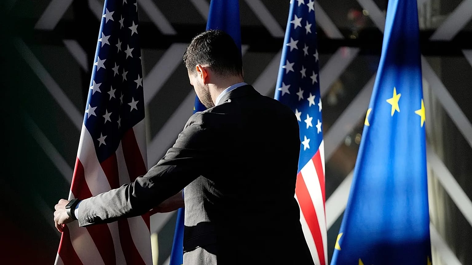 A worker adjusts the US and EU flags at the European Council building in Brussels, 4 April, 2023