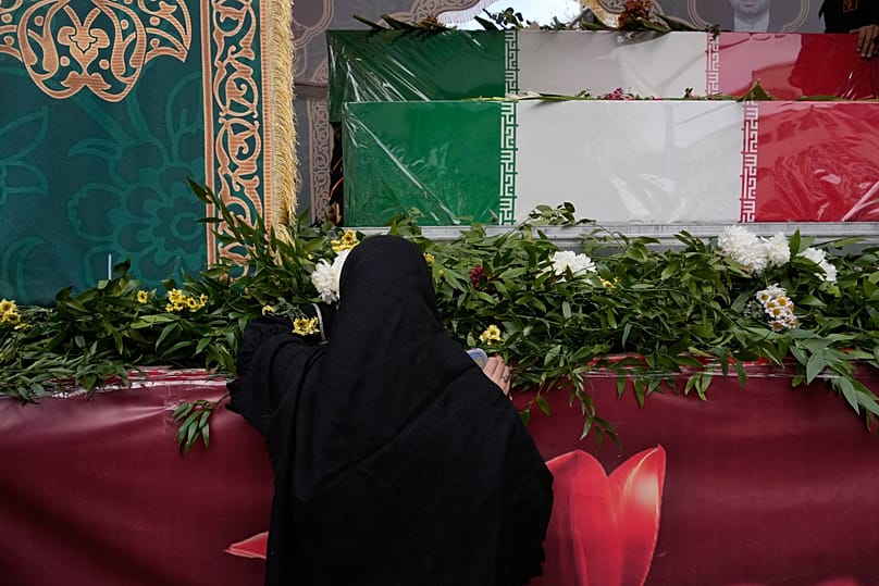 A woman mourns next to the flag-draped coffins of a group of security forces in Tehran, 14 January, 2026