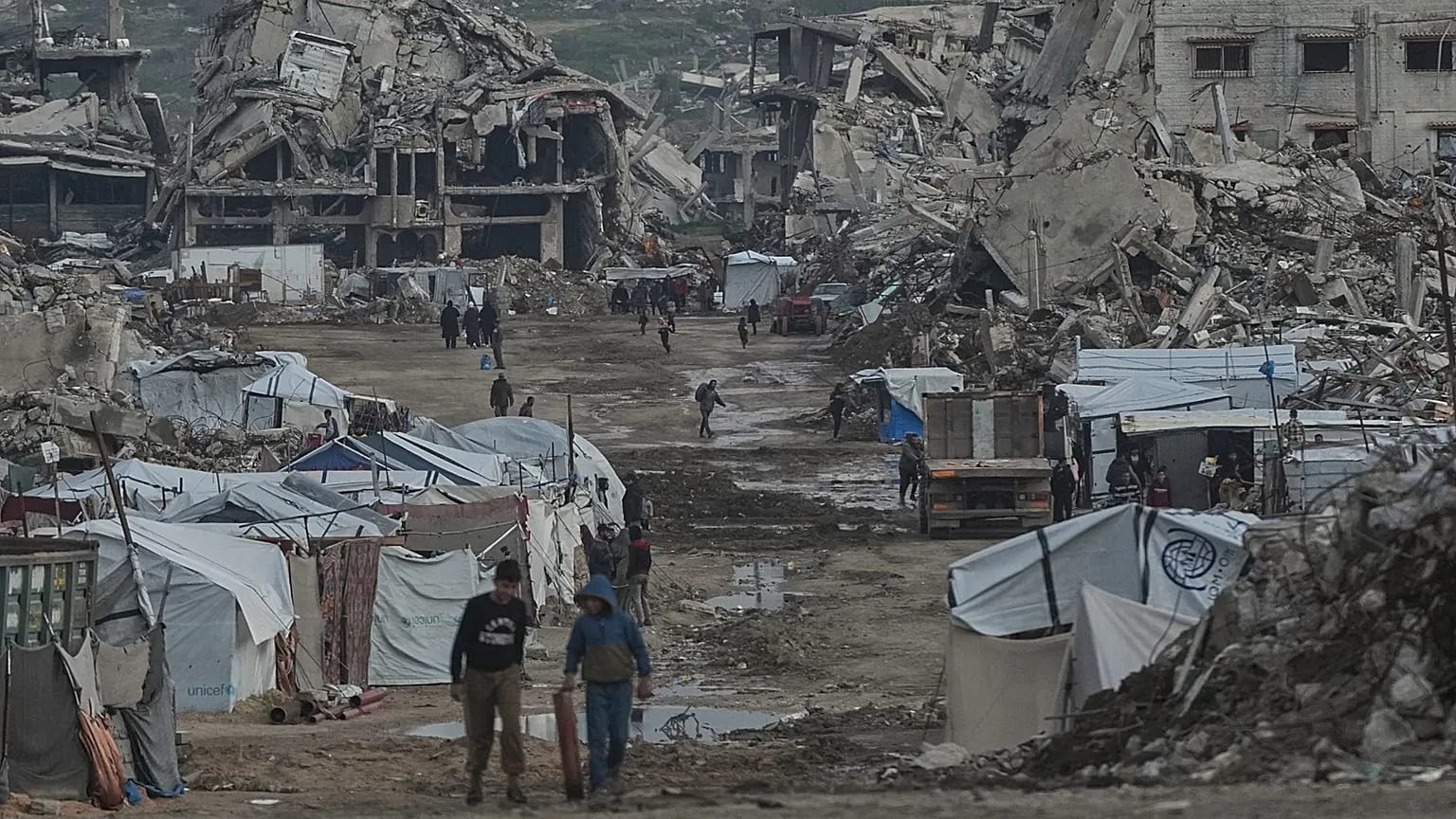 Palestinians walk amid buildings destroyed by Israeli air and ground operations in Gaza City, 14 January, 2026