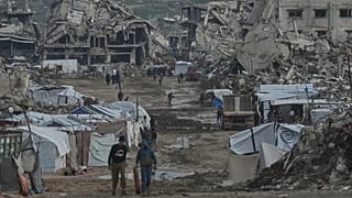 Palestinians walk amid buildings destroyed by Israeli air and ground operations in Gaza City, 14 January, 2026