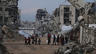 فلسطينيون يسيرون بين مبانٍ دمّرتها الغارات الجوية والعمليات البرية الإسرائيلية في حيّ الزيتون بمدينة غزة، الأربعاء 14 كانون الثاني/يناير 2026. 