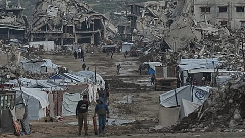 Palestinians walk amid buildings destroyed by Israeli air and ground operations in Gaza City, 14 January, 2026