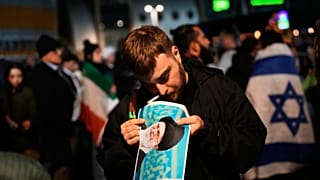 أحد المتظاهرين يشعل سيجارة بملصق تظهر عليه صورة المرشد الإيراني علي خامنئي، خلال تظاهرة دعم للاحتجاجات المناهضة للحكومة في إيران، في مدينة حولون داخل إسرائيل، في 14 يناير 2026