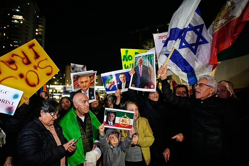 متظاهرون يلوّحون بعلم إيران ما قبل الثورة والعلم الإسرائيلي، إلى جانب صور ولي عهد إيران السابق رضا بهلوي