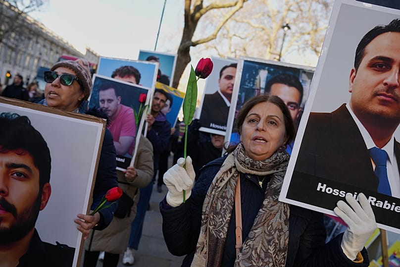 Protesters hold up placards with pictures of victims as they demonstrate in support of anti-government protests in Iran, outside Downing Street, in London, Wednesday, Jan. 14,