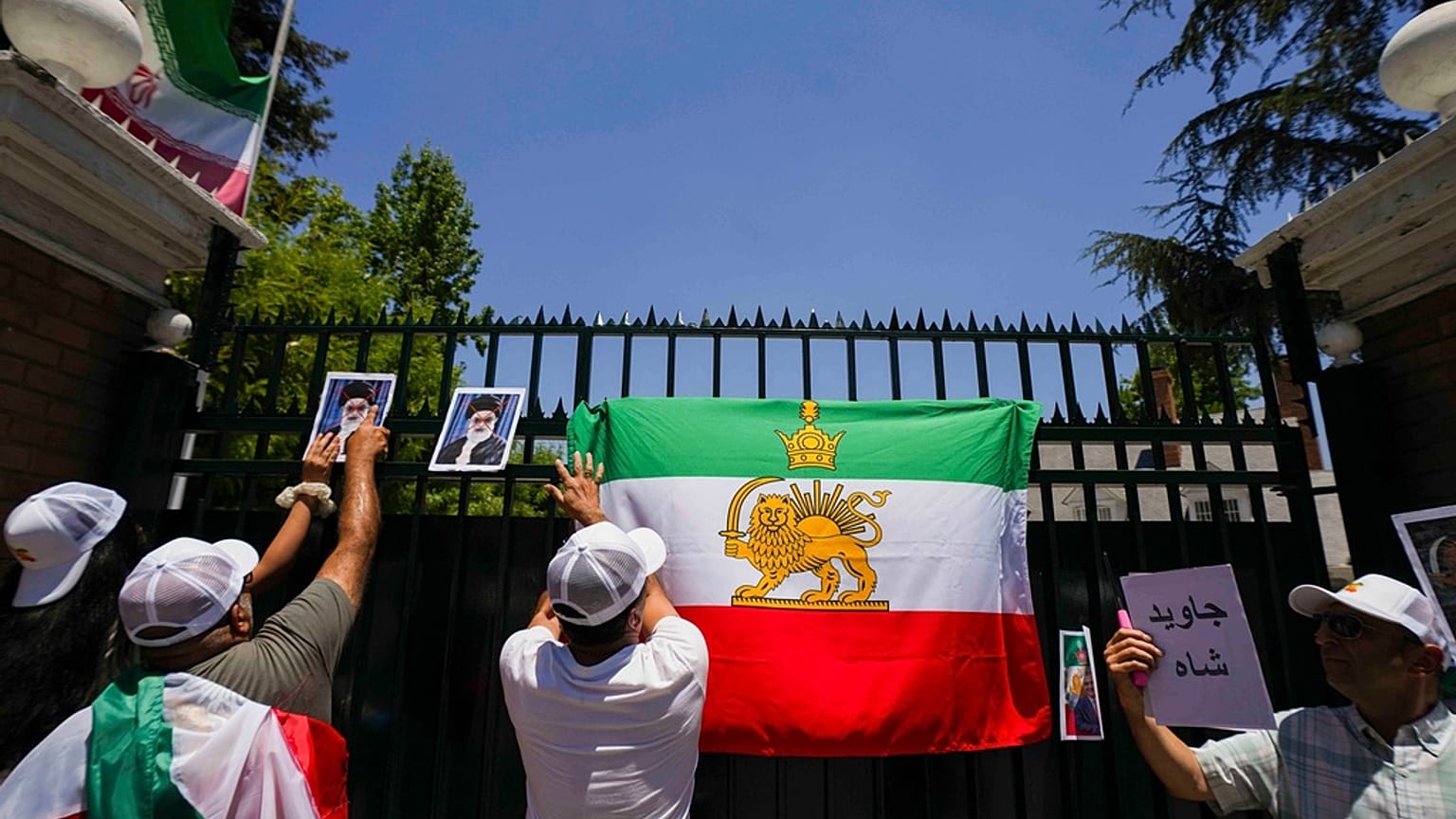 وضع متظاهرون ملصقات لولي العهد الإيراني المنفي رضا بهلوي والمرشد الأعلى الإيراني آية الله علي خامنئي خلال مسيرة دعماً للاحتجاجات المناهضة للحكومة في إيران، خارج السفارة الإيرا