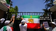 وضع متظاهرون ملصقات لولي العهد الإيراني المنفي رضا بهلوي والمرشد الأعلى الإيراني آية الله علي خامنئي خلال مسيرة دعماً للاحتجاجات المناهضة للحكومة في إيران، خارج السفارة الإيرا