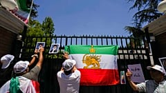 وضع متظاهرون ملصقات لولي العهد الإيراني المنفي رضا بهلوي والمرشد الأعلى الإيراني آية الله علي خامنئي خلال مسيرة دعماً للاحتجاجات المناهضة للحكومة في إيران، خارج السفارة الإيرا