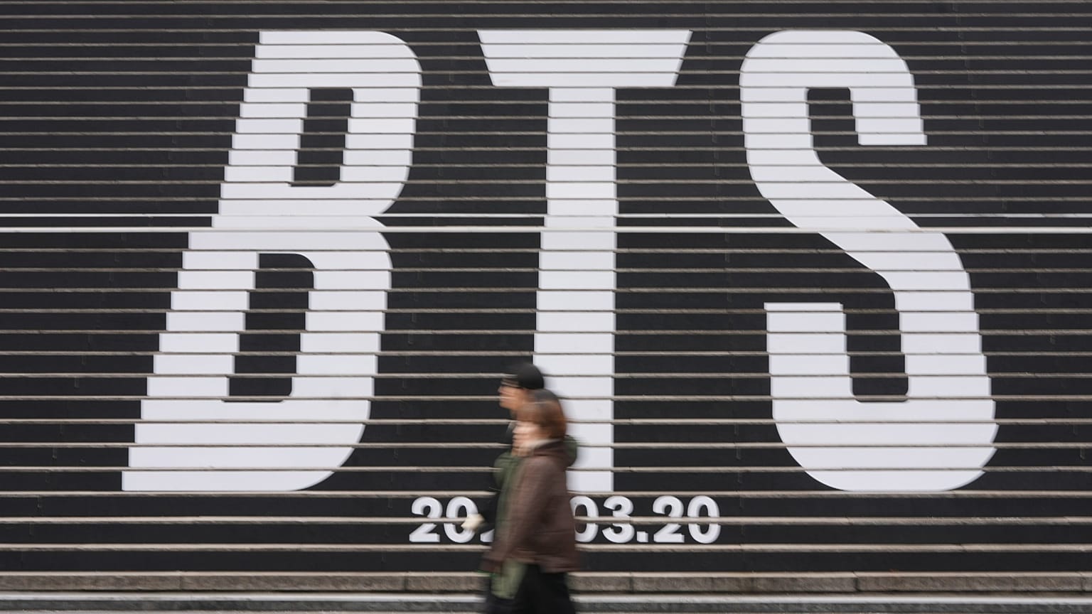 People walk by the huge letters of BTS at downtown Seoul, South Korea, Thursday, Jan. 15, 2026