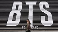 La gente pasa junto a las enormes letras de BTS en el centro de Seúl, Corea del Sur, el jueves 15 de enero de 2026