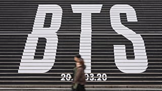 People walk by the huge letters of BTS at downtown Seoul, South Korea, Thursday, Jan. 15, 2026