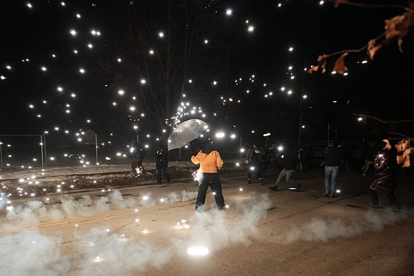 A protester holds an umbrella as sparks fly from a flash bang deployed by law enforcement on Wednesday, Jan. 14, 2026, in Minneapolis. 