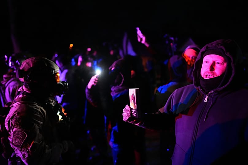 A protester holds a copy of the U.S. Constitution in front of federal law enforcement after a shooting on Wednesday, Jan. 14, 2026, in Minneapolis.