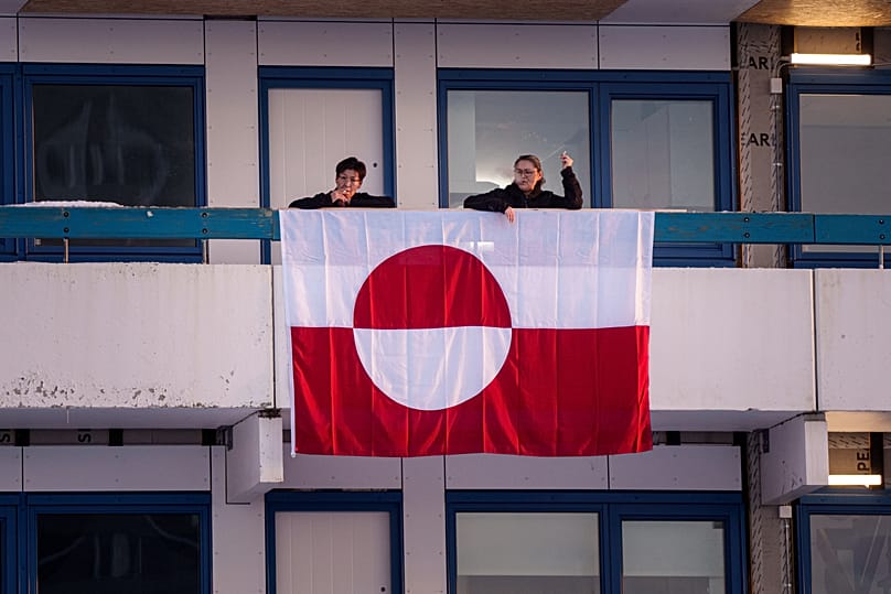 Des femmes font une pause cigarette sur un balcon orné du drapeau national groenlandais à Nuuk, au Groenland, le mercredi 14 janvier 2026.