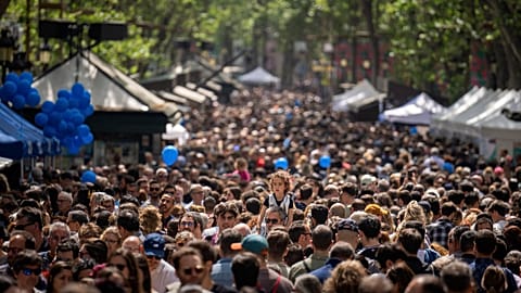 FILE - People crowd along the historic La Rambla promenade of Barcelona as Catalans celebrate the day of their patron Sant Jordi, Spain, Sunday, April 23, 2023. 