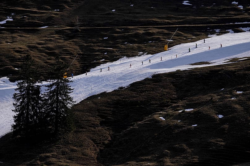  People ski on a hill with manufactured snow near Bayrischzell, Germany.