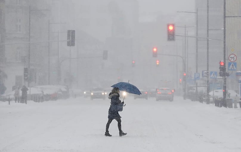 A woman uses an umbrella for protection against falling snow in Warsaw, 8 February, 2021 