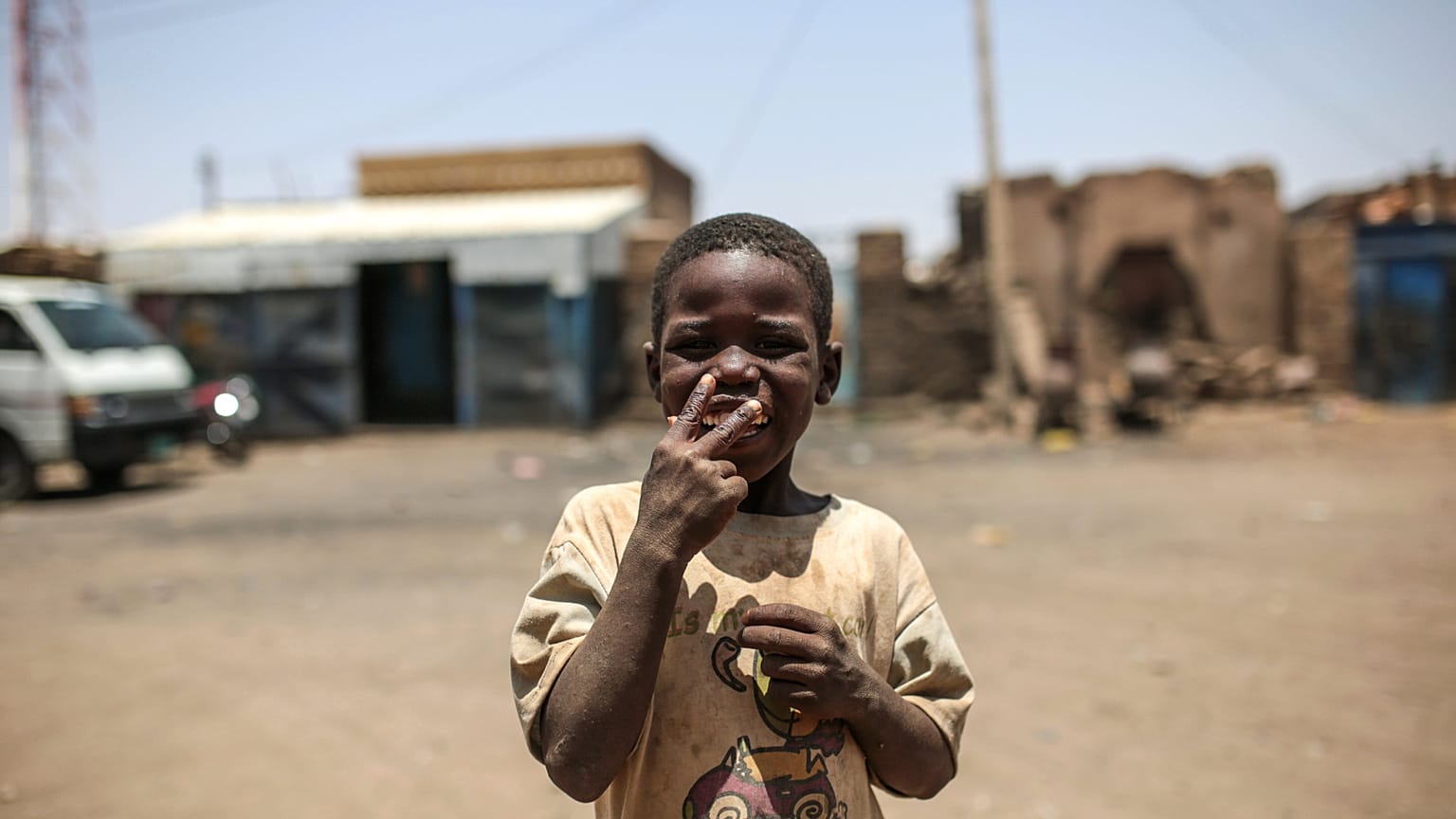 طفل سوداني يشير إلى الكاميرا ليطلب سيجارة، خارج منزله في إزبا. (صورة من وكالة أسوشيتد برس/مصعب الشامي)