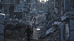 فلسطينيون يسيرون وسط مبانٍ دمّرتها الغارات الجوية والعمليات البرية الإسرائيلية في مدينة غزة، الخميس 15 يناير/كانون الثاني 2026.