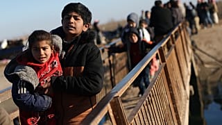 نازحون سوريون يسيرون لعبور نهر بالقرب من قرية جريرة الإمام، في ريف حلب الشرقي في دير حفر، سوريا، الخميس 15 يناير 2026. (صورة من وكالة أسوشيتد برس/غيث السيد)