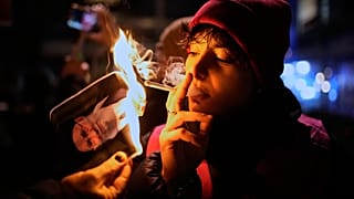 متظاهر في ألمانيا يشعل سيجارته بملصق للمرشد الإيراني علي خامنئي تضامناً مع الاحتجاجات في إيران