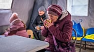 A woman gets warm with a hot cup of tea at an emergency center set up to support people during power outages caused by Russia's regular air attacks on the country