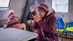 Eine Frau wärmt sich in einem Notfallzentrum mit einer heißen Tasse Tee. Das Zentrum hilft Menschen bei Stromausfällen durch Russlands regelmäßige Luftangriffe auf das Land.