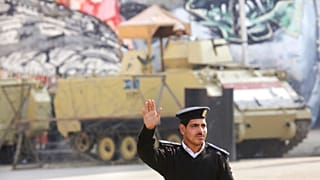 شرطي مصري وخلفه عربة مصفحة للجيش المصري