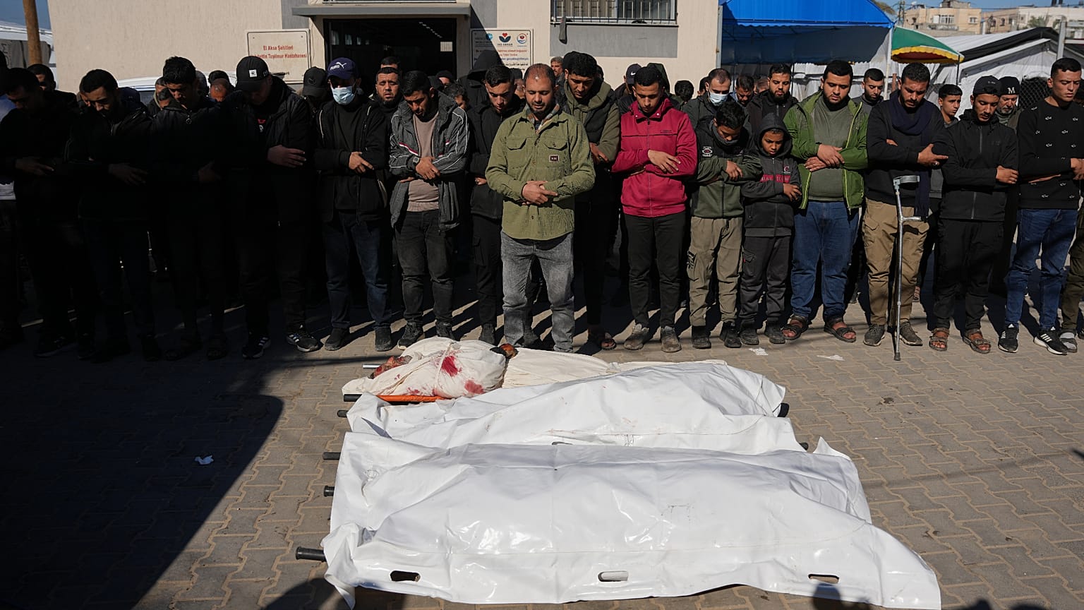 Palestinians pray beside the bodies of members of the al-Hawli family, killed in an Israeli military strike