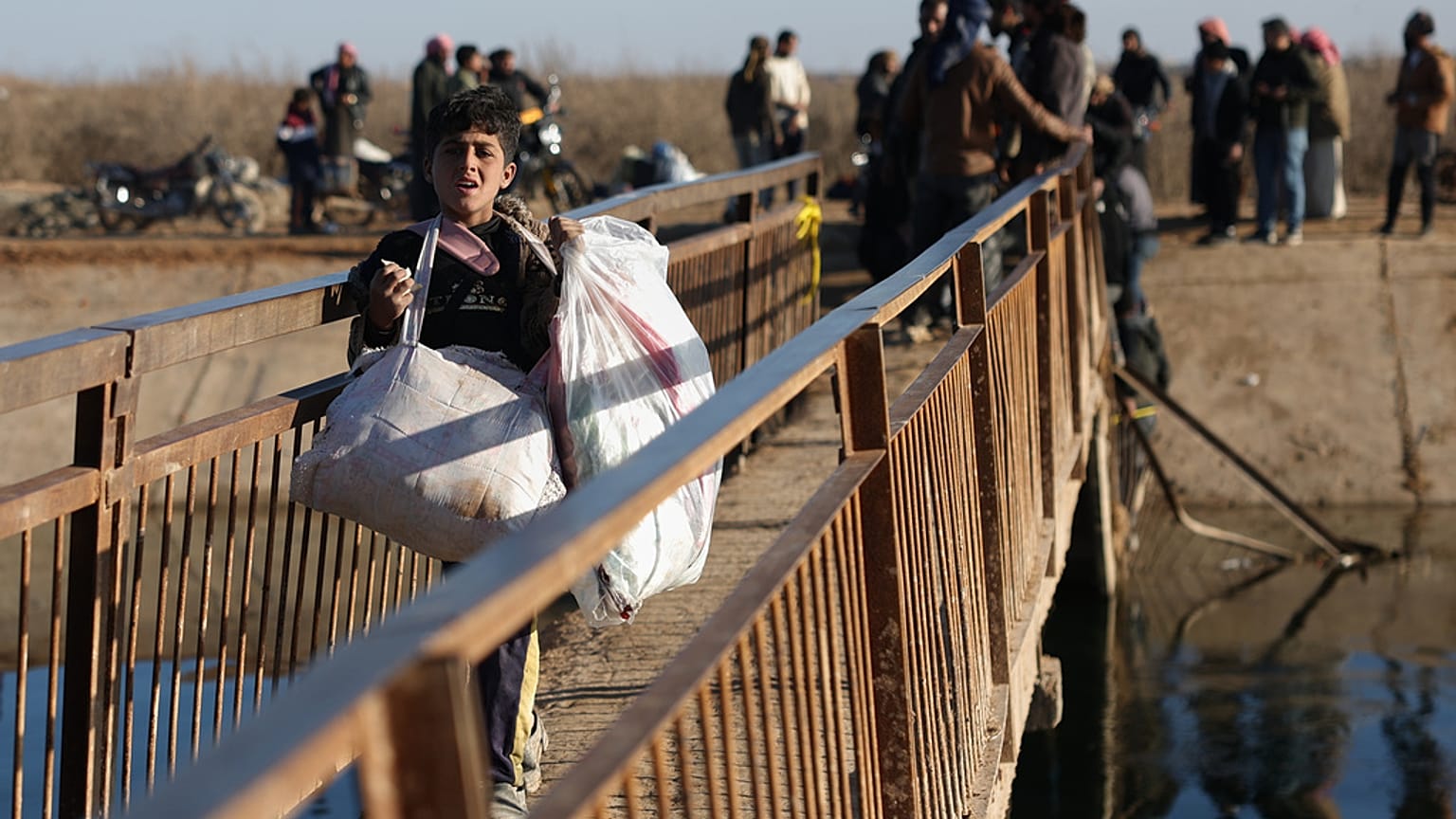 نازحون سوريون يسيرون للعبور عند معبر نهري بالقرب من قرية جريرات الإمام بريف حلب الشرقي قرب دير حافر، سوريا، الخميس 15 يناير 2026. 