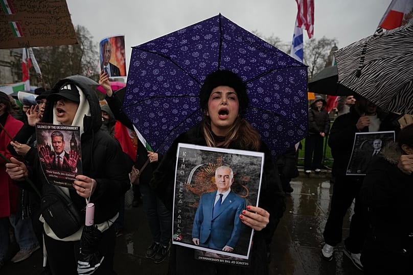 متظاهرون يرفعون لافتات تحمل صورة رضا بهلوي، خلال تظاهرة أمام مبنى البرلمان في لندن، بتاريخ 13 يناير 2026.