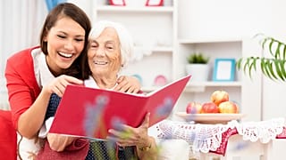 امرأة مسنّة تتصفح كتاباً برفقة شابة