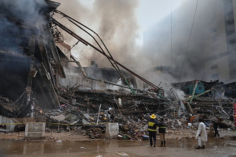 Firefighters examine a collapsed portion of a multi-story shopping mall following a massive fire in Karachi, 18 January, 2026