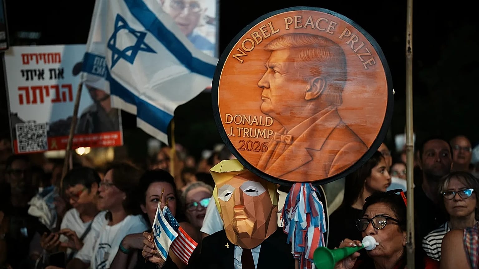A man wearing a mask resembling US President Donald Trump holds a sign designed like a Nobel Peace Prize in Tel Aviv, 11 October, 2025