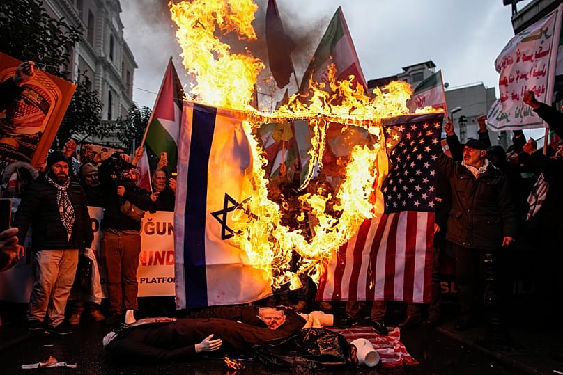 People burn US and Israel flags during a rally in support of the Iranian government in Istanbul, 18 January, 2026