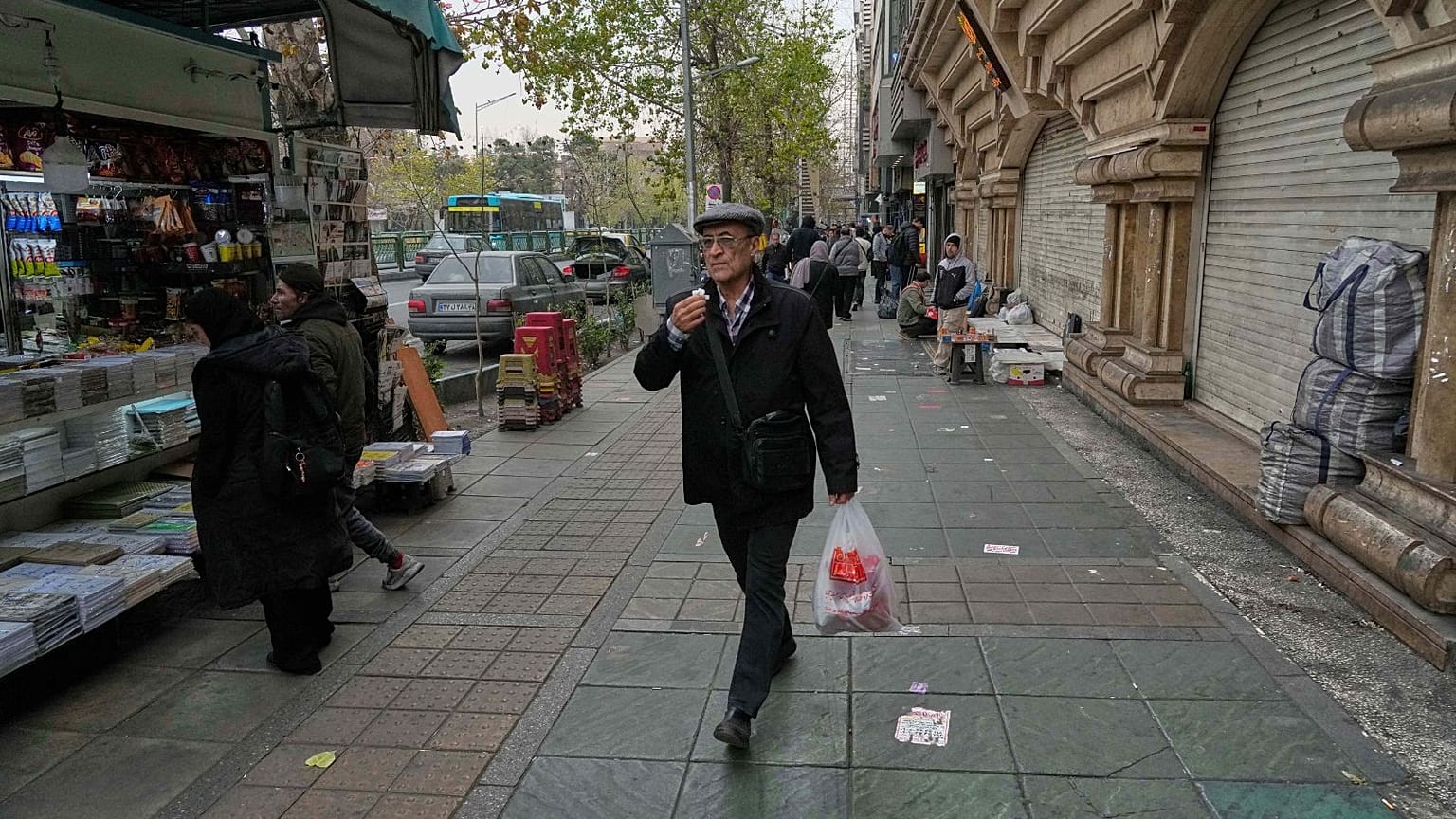 A man walks on a sidewalk in downtown Tehran, Iran, Thursday, Jan. 15, 2026