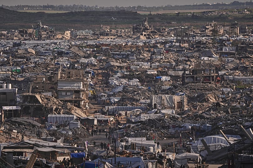 Makeshift tents shelter displaced Palestinians stand among buildings destroyed by Israeli air and ground operations in Gaza City, 15 January, 2026