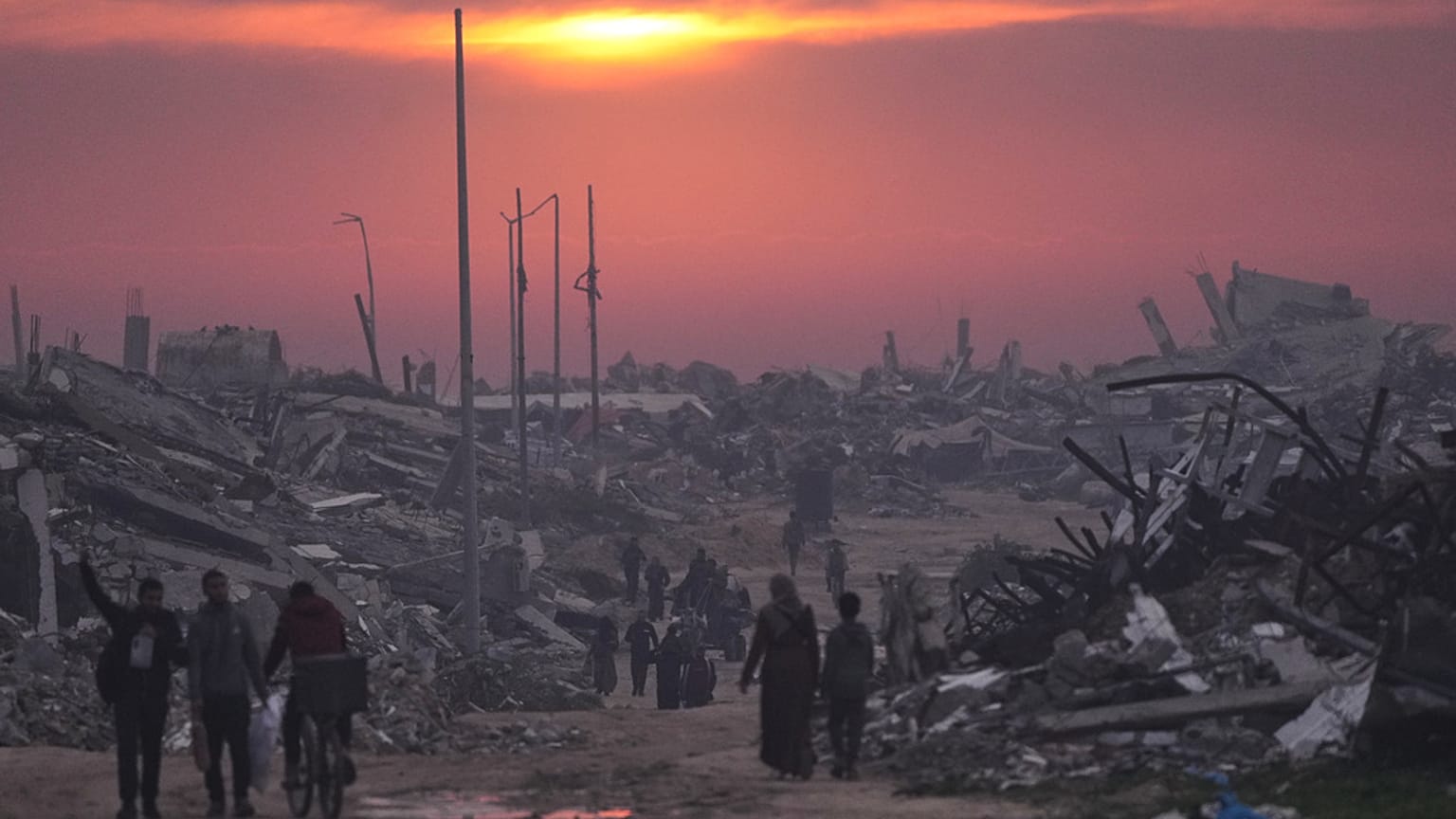 فلسطينيون يسيرون بين أنقاض المباني المدمرة في مدينة غزة، الأحد 4 يناير 2026